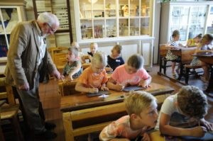 Het klaslokaal van De Meestoof is aangekleed met schoolbanken, diverse Isings-kaarten, de kroontjespen met houder