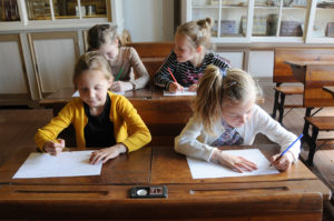 Het klaslokaal van De Meestoof is aangekleed met schoolbanken, diverse Isings-kaarten, de kroontjespen met houder